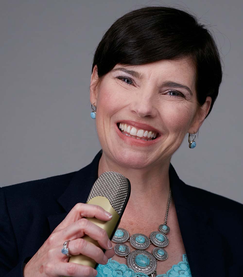 Christine smiling, with microphone in hands